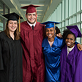  High school Profile of a Graduate committee members pose for a picture in graduation gowns.